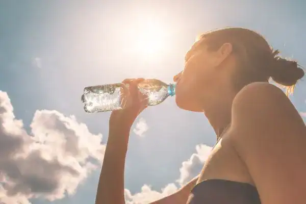 Hydration: The Secret Ingredient for a Toned Stomach and Enhanced Fitness 3 Image of woman drinking water to hydrate Pinner after run.