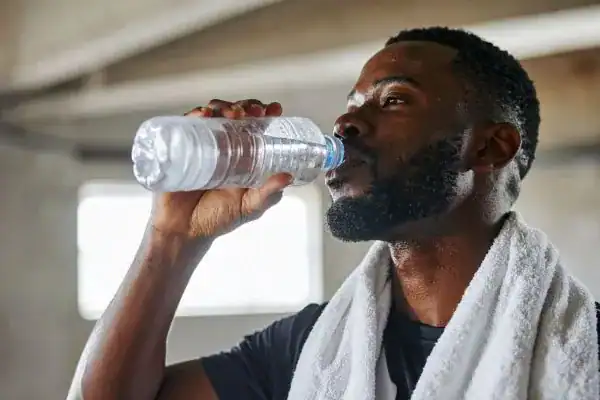 Image of man drinking water to improve hydration Pinner after work out.